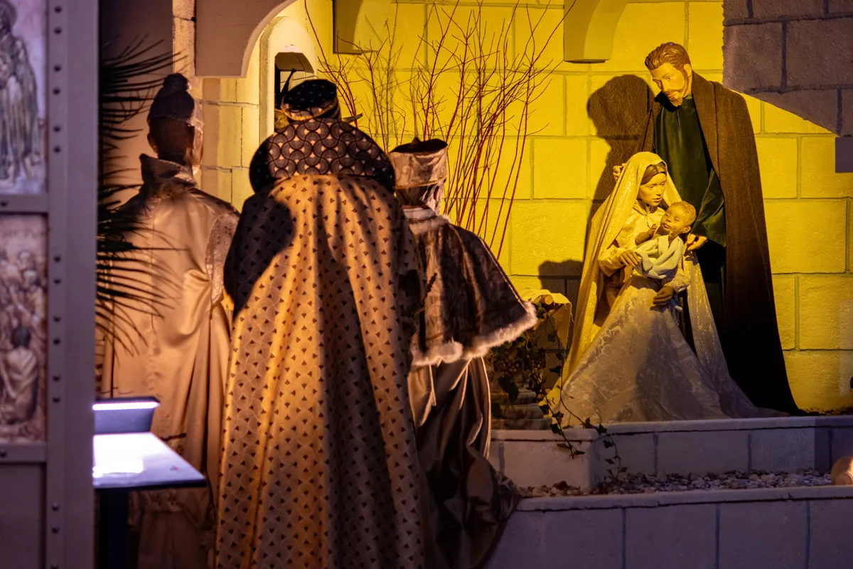 Kerststal in de Sint-Janskathedraal met engelen en verlichte kerstbomen